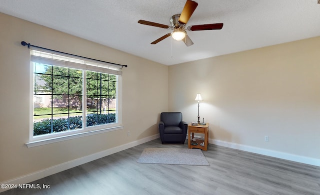 sitting room featuring light hardwood / wood-style floors, a textured ceiling, and ceiling fan