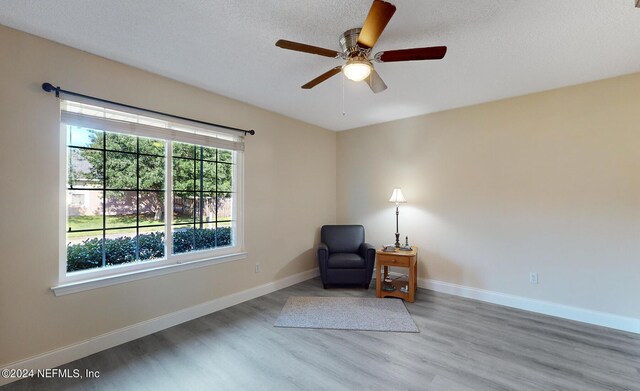 sitting room featuring wood finished floors, ceiling fan, baseboards, and a textured ceiling