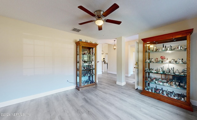 empty room featuring a textured ceiling, light hardwood / wood-style floors, and ceiling fan