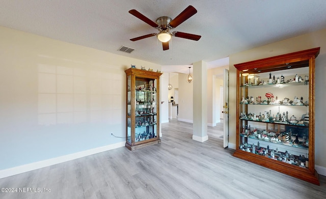 unfurnished room featuring a ceiling fan, wood finished floors, baseboards, and a textured ceiling