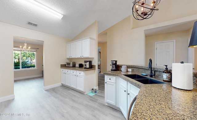 kitchen with a chandelier, a sink, light wood-style flooring, lofted ceiling, and white cabinets