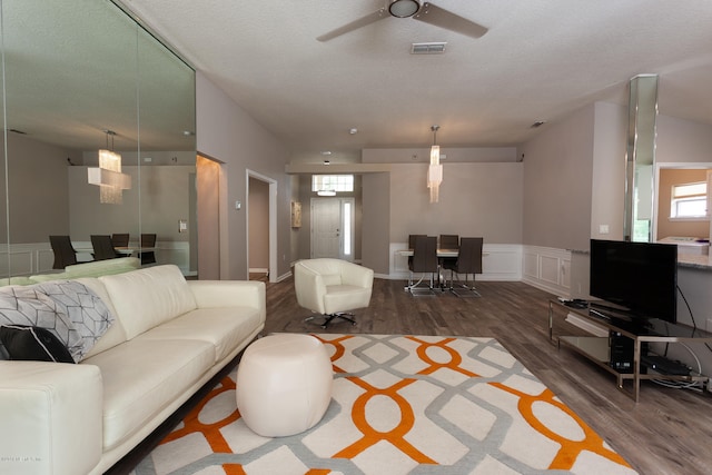 living room featuring a textured ceiling, dark wood-type flooring, and ceiling fan