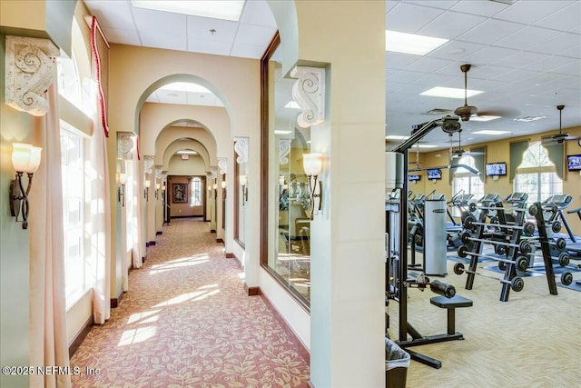 workout area with a drop ceiling, carpet, and a wealth of natural light
