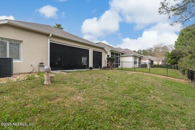 rear view of property featuring fence, central AC, stucco siding, a garage, and a lawn