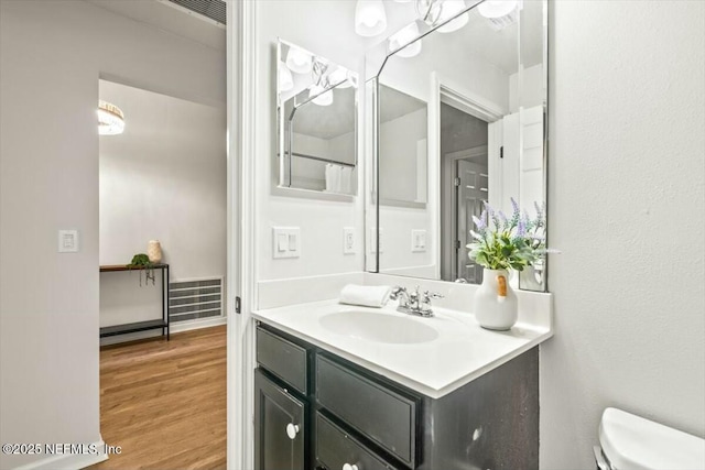 bathroom featuring toilet, vanity, and wood finished floors