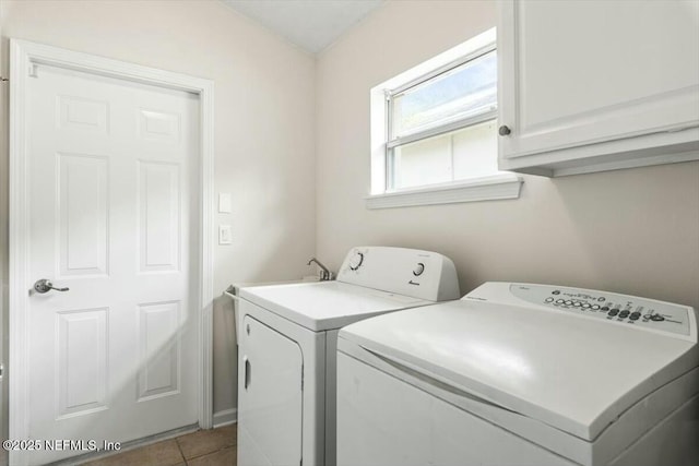 washroom featuring light tile patterned flooring, washing machine and dryer, and cabinet space