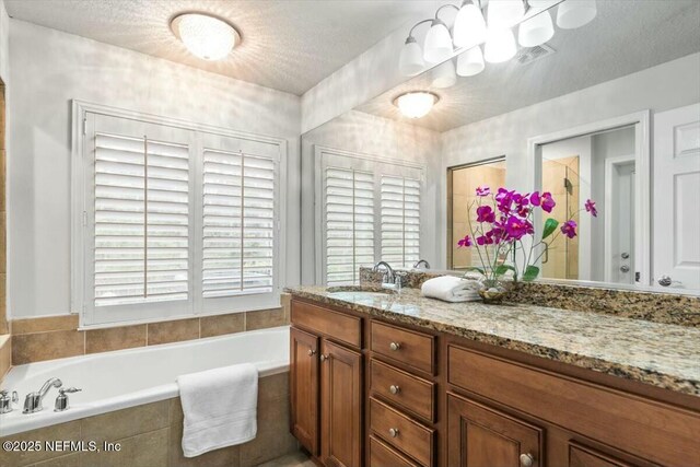 full bathroom featuring vanity, a bath, and a textured ceiling
