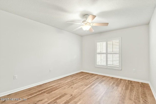 spare room with light wood-type flooring, baseboards, a textured ceiling, and a ceiling fan