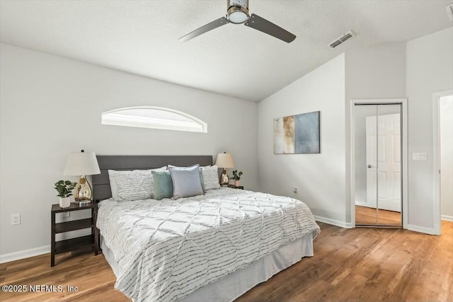 bedroom with visible vents, wood finished floors, baseboards, and vaulted ceiling