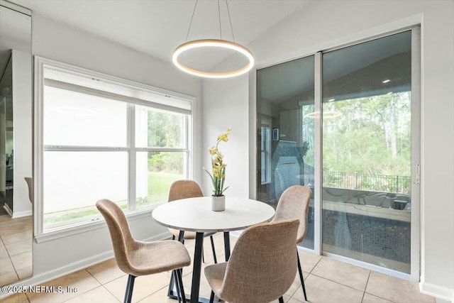 dining room featuring light tile patterned floors, baseboards, and vaulted ceiling