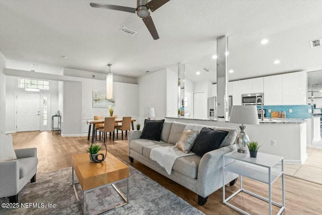 living area featuring light wood finished floors, visible vents, recessed lighting, and a ceiling fan