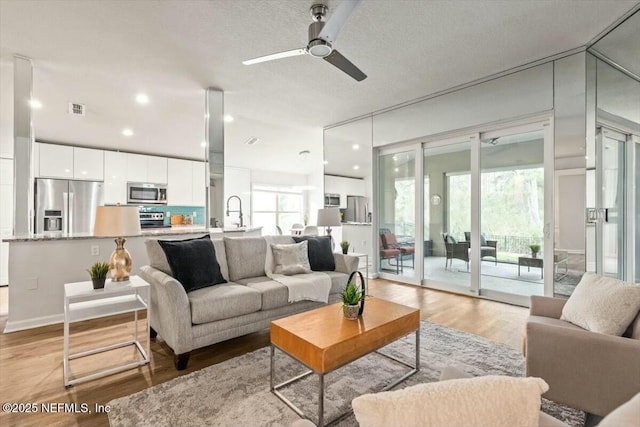 living area with recessed lighting, visible vents, ceiling fan, and light wood finished floors