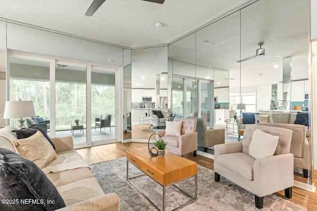 living room with wood finished floors, a ceiling fan, and a healthy amount of sunlight