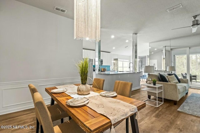 dining space with visible vents, wainscoting, lofted ceiling, and wood finished floors