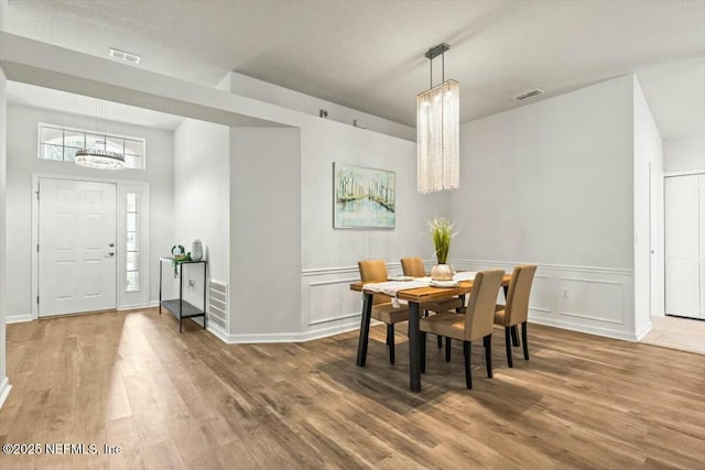 dining area featuring an inviting chandelier, wood finished floors, and visible vents
