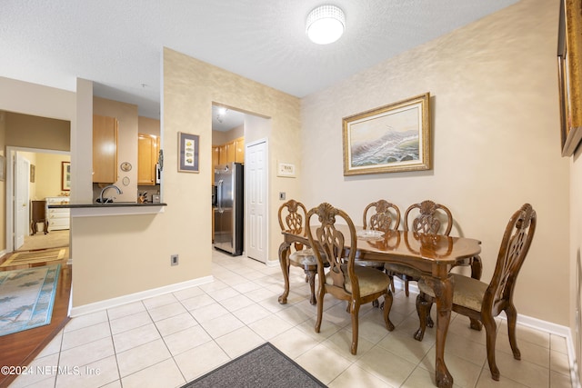 dining area with a textured ceiling and light tile patterned flooring