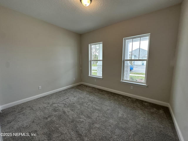 carpeted spare room with a textured ceiling and baseboards