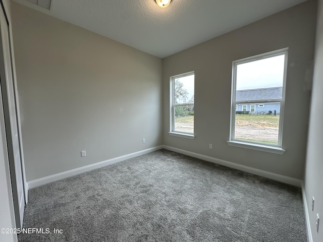 carpeted spare room featuring baseboards and a textured ceiling