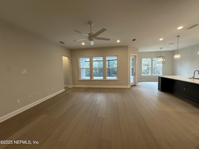 unfurnished living room featuring ceiling fan, wood finished floors, visible vents, and baseboards