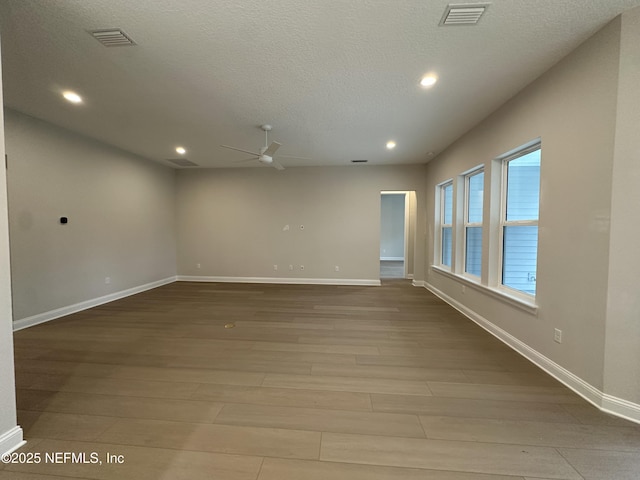 empty room featuring ceiling fan, a textured ceiling, light wood-type flooring, and visible vents