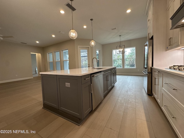 kitchen featuring light wood-type flooring, stainless steel appliances, a sink, and light countertops