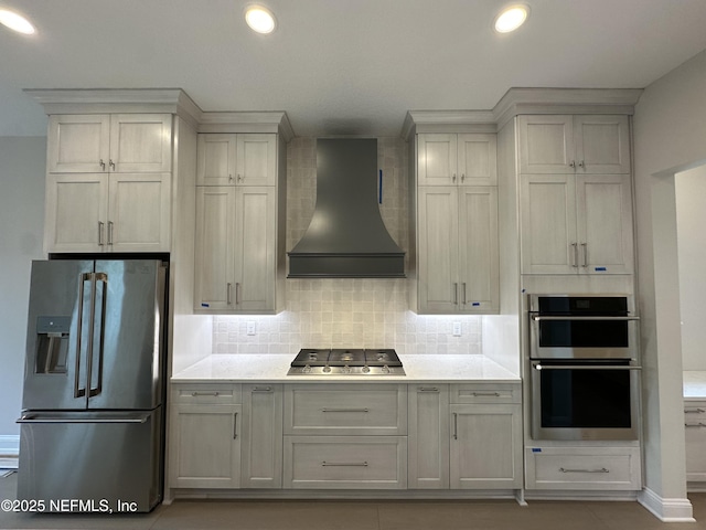 kitchen featuring stainless steel appliances, decorative backsplash, light countertops, and custom range hood