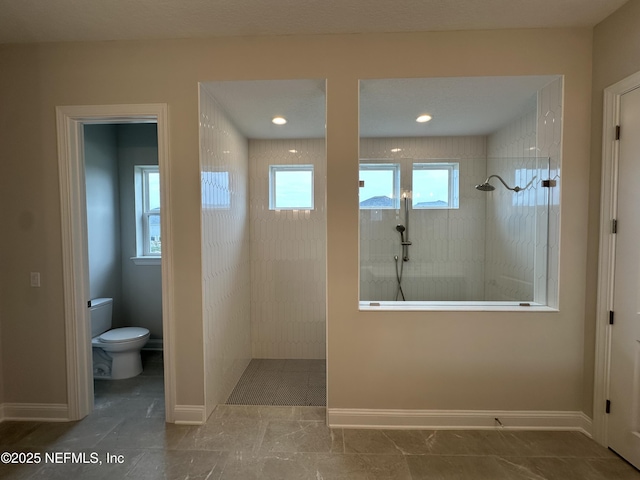 bathroom with toilet, baseboards, and a walk in shower