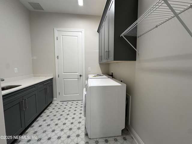 laundry area with cabinet space, baseboards, visible vents, light floors, and a sink