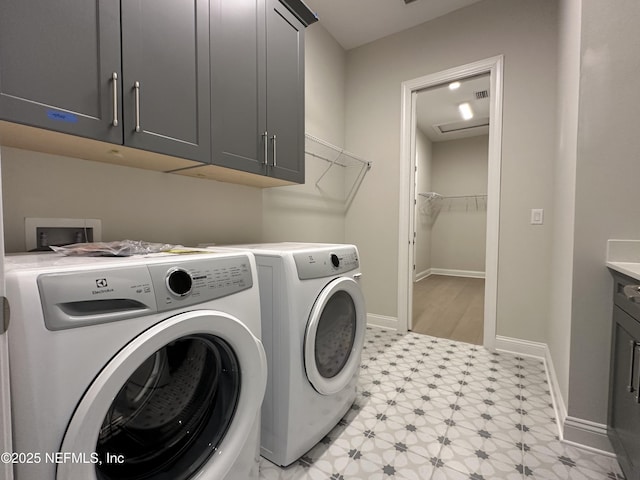 clothes washing area with light floors, washer and clothes dryer, cabinet space, and baseboards