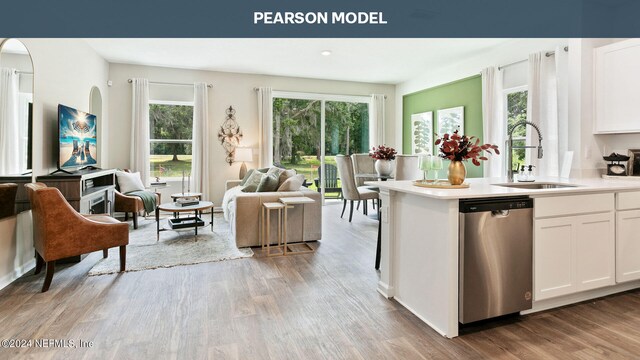 kitchen with light wood finished floors, dishwasher, a sink, open floor plan, and white cabinetry
