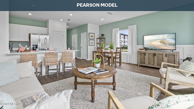 living room featuring wainscoting, dark wood-style floors, recessed lighting, and visible vents
