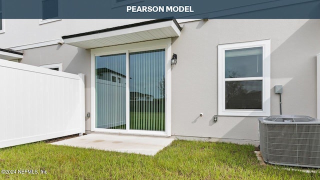view of exterior entry with fence, cooling unit, and stucco siding
