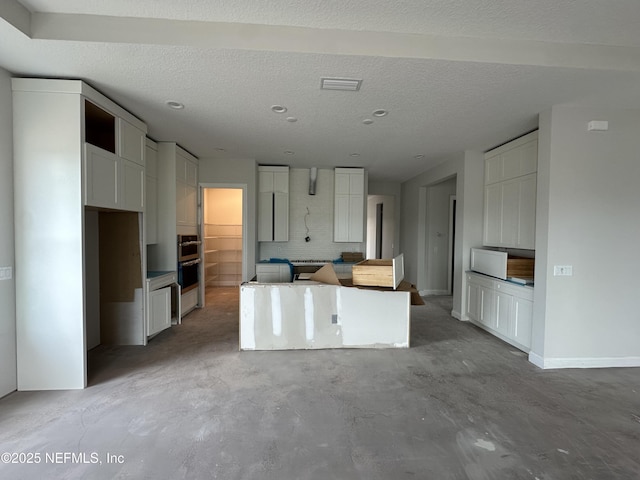 kitchen featuring white cabinetry, a center island, and a textured ceiling