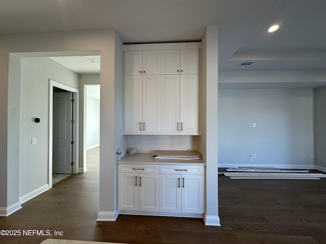 kitchen featuring dark wood-style floors, baseboards, white cabinetry, and light countertops