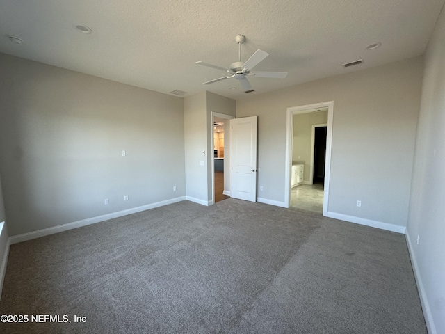 unfurnished bedroom with baseboards, visible vents, ceiling fan, a textured ceiling, and dark carpet