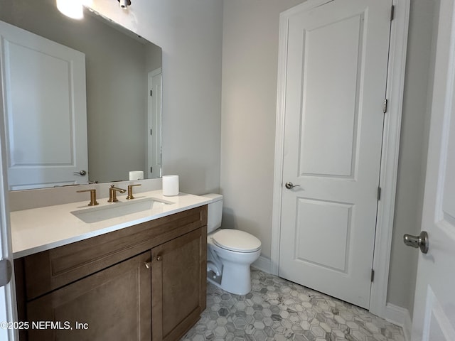 half bath featuring toilet, baseboards, and vanity