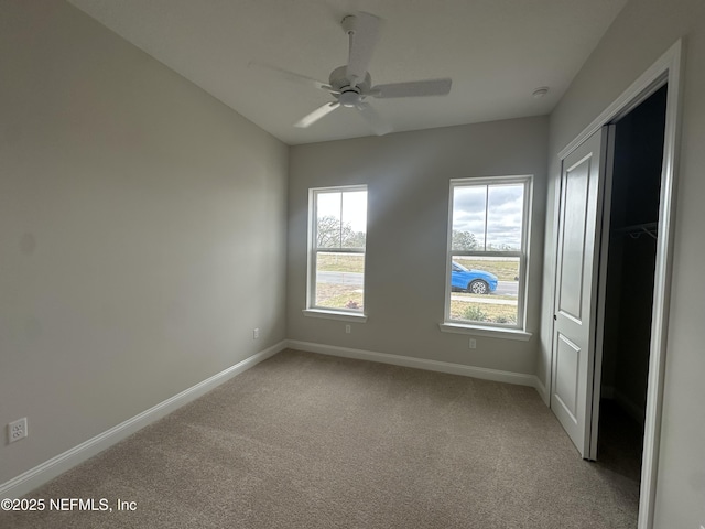 empty room with light colored carpet, ceiling fan, and baseboards