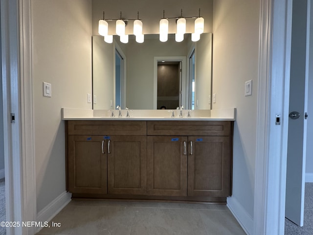 bathroom with tile patterned floors, a sink, baseboards, and double vanity