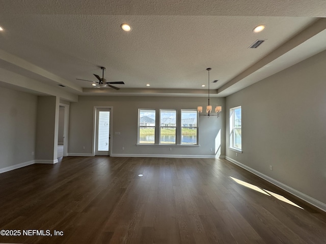 spare room featuring a textured ceiling, a raised ceiling, dark wood finished floors, and baseboards