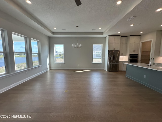 kitchen featuring baseboards, visible vents, dark wood-style flooring, a tray ceiling, and stainless steel appliances