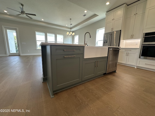 kitchen featuring dark wood-type flooring, open floor plan, appliances with stainless steel finishes, gray cabinets, and a raised ceiling