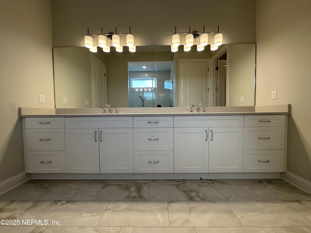 full bathroom with double vanity, marble finish floor, a sink, and a shower with shower door