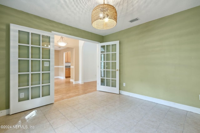 empty room featuring french doors, hardwood / wood-style floors, and a textured ceiling