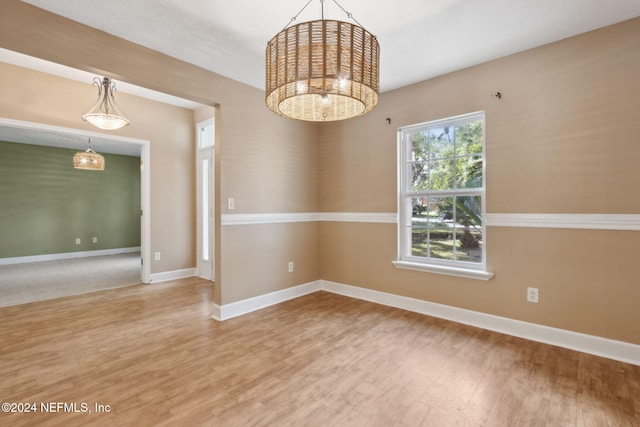 spare room featuring wood-type flooring and a notable chandelier