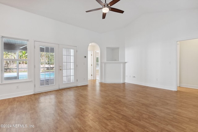 unfurnished living room featuring light hardwood / wood-style floors, ceiling fan, high vaulted ceiling, and french doors