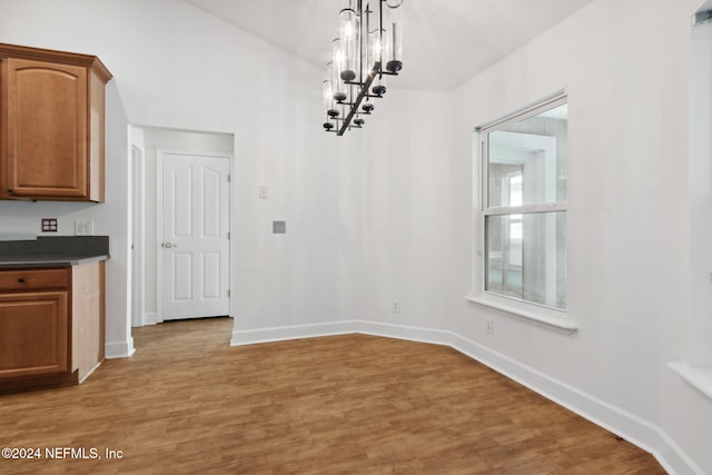 unfurnished dining area with hardwood / wood-style floors and an inviting chandelier