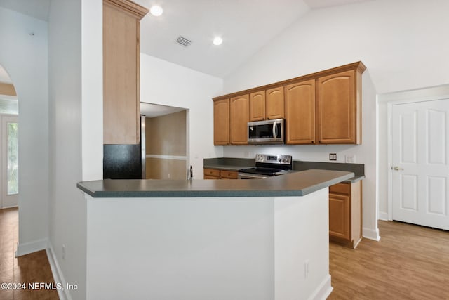 kitchen featuring stainless steel appliances, lofted ceiling, light hardwood / wood-style floors, and kitchen peninsula