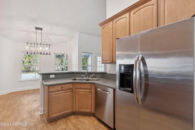 kitchen featuring pendant lighting, a wealth of natural light, stainless steel appliances, and light hardwood / wood-style floors