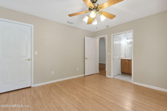 unfurnished bedroom with ensuite bathroom, ceiling fan, and light wood-type flooring