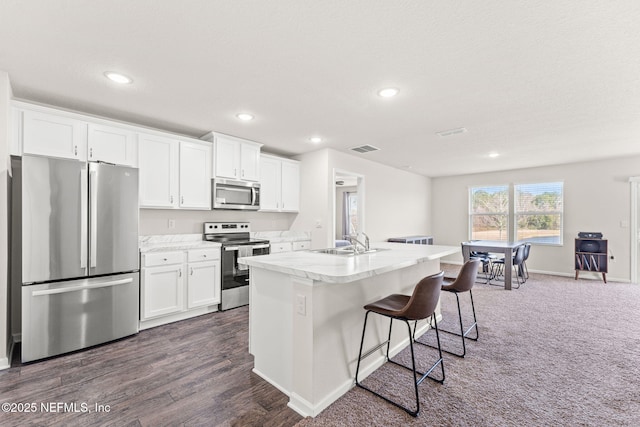 kitchen featuring a breakfast bar, sink, appliances with stainless steel finishes, an island with sink, and white cabinets